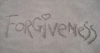 The word forgiveness written in grey sand